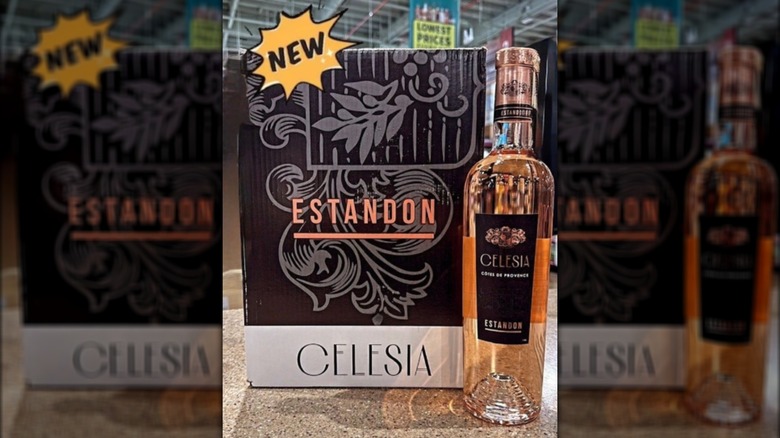 A bottle of rosé wine in front of case on display inside a liquor store.