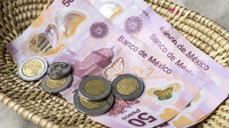 Pesos notes and coins in a basket