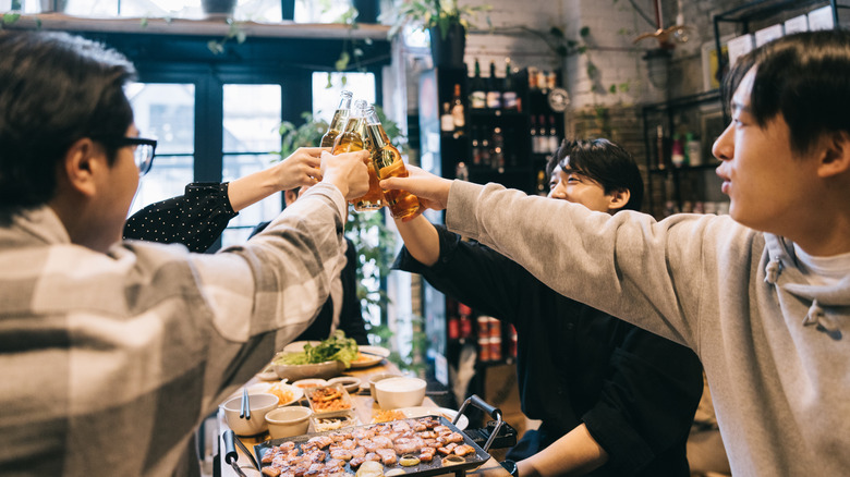 A group cheersing beers at a Korean bbq