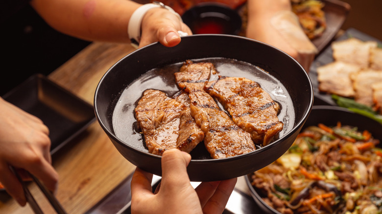 Hands holding a bowl of cooked meats
