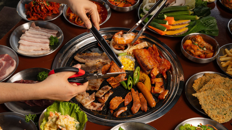 Person using scissors to slice food at a Korean barbecue restaurant