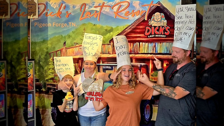 A family posing with their white hats with insults at Dick's Last Resort