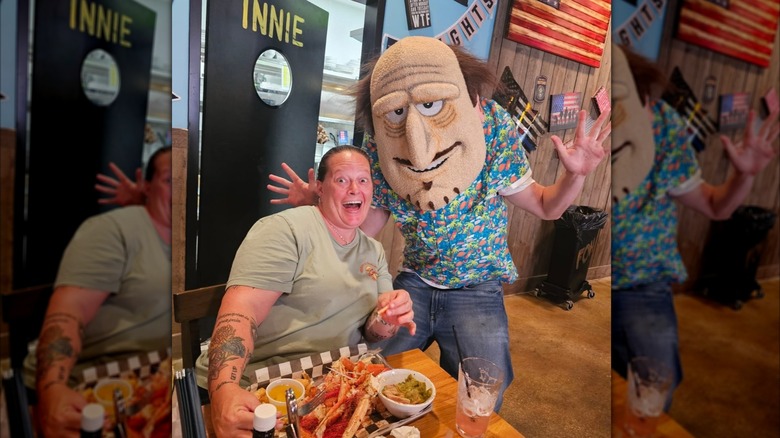 A woman happily posing with an employee wearing a Dick's Last Resort mask