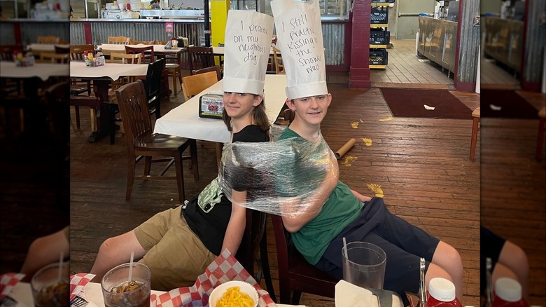 Two teenage boys plastic-wrapped to chairs