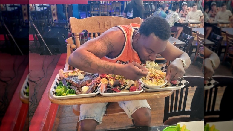 A man in a high chair eating Dick's Big Meat Challenge