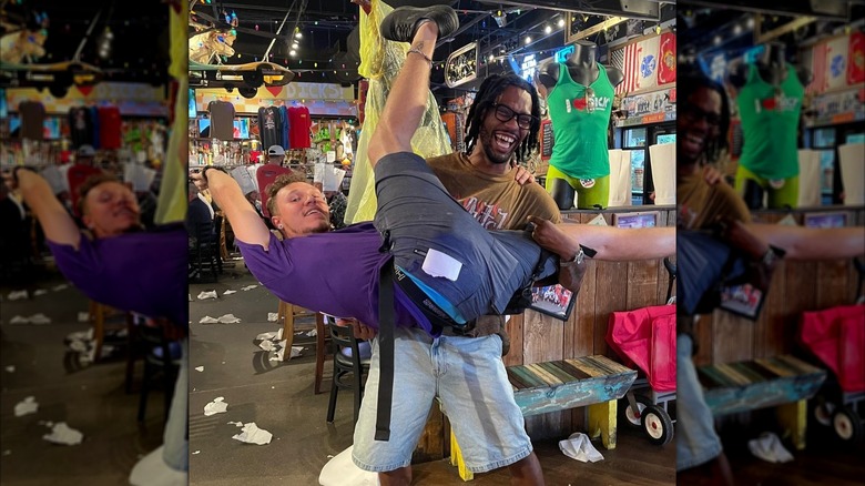 One man lifting up another man who's spreading his legs at Dick's Last Resort