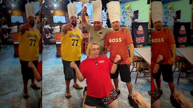 A Dick's Last Resort waiter posing suggestively with three amused guests