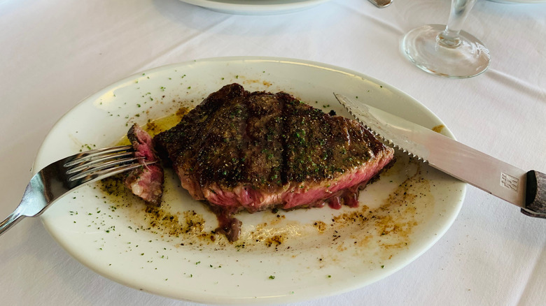 A Ruth's Chris steak on a plate with a knife and fork