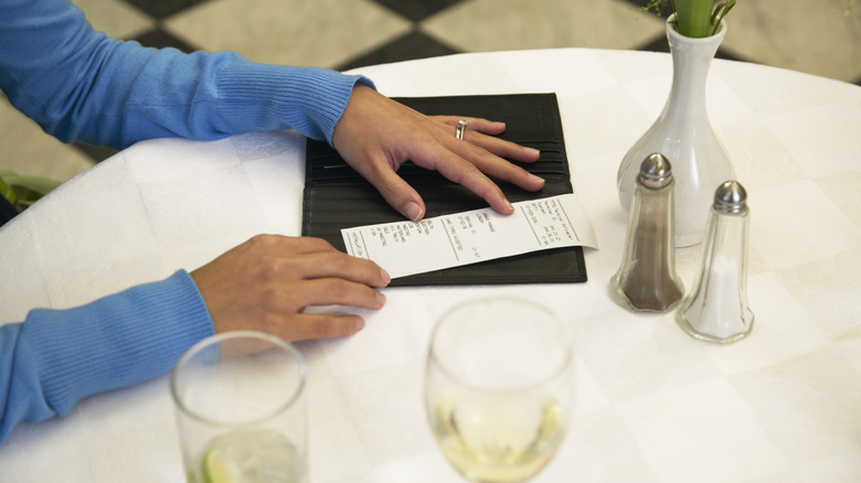 A person reviewing a restaurant bill