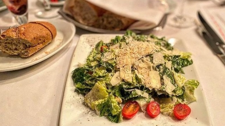 A plate of Ruth's Chris Caesar salad with a piece of bread