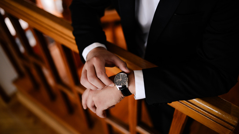 A man in a suit looking down at his wristwatch