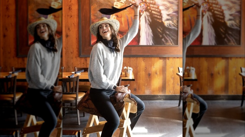 a woman sitting on a Western saddle mounted to a wooden stand