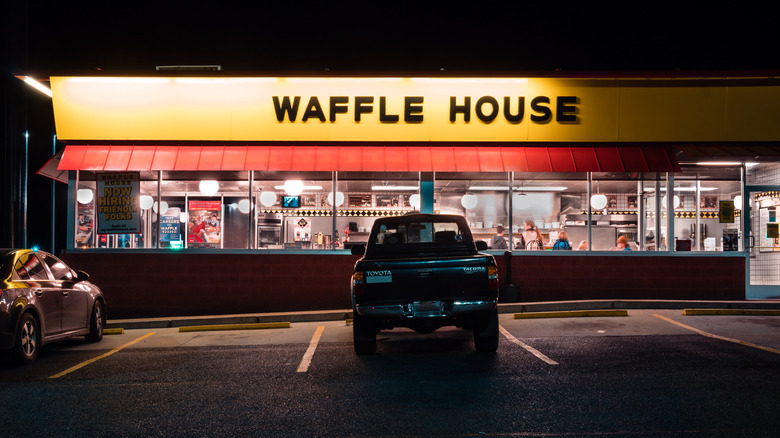 A Waffle House restaurant lit up in the dark parking lot