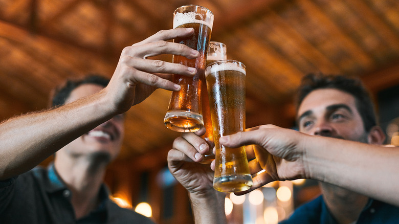 A group of men clinking their beer glasses together smiling