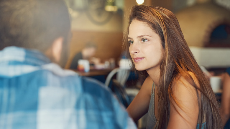 Woman looks at a man as she sits with him at a restaurant.