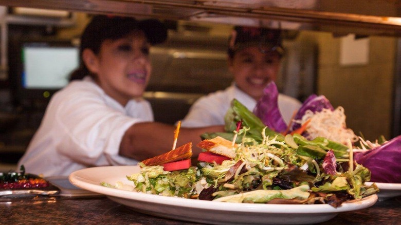 Cooks prepare salads at a Cheesecake Factory