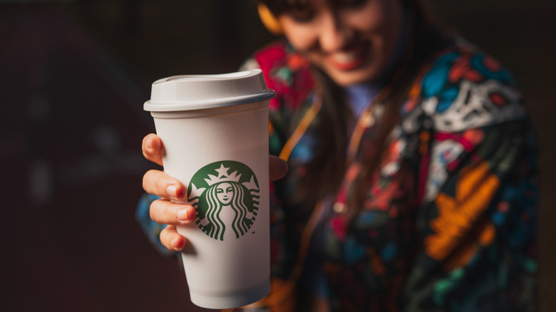 Woman holding out white Starbucks cup