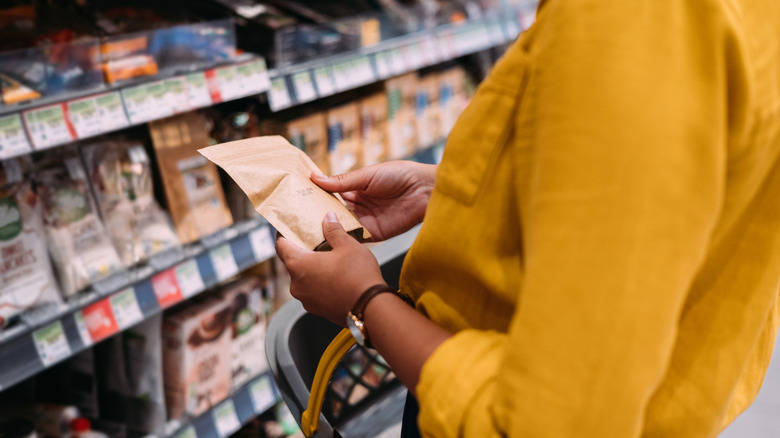 Woman checking a food package in grocery store