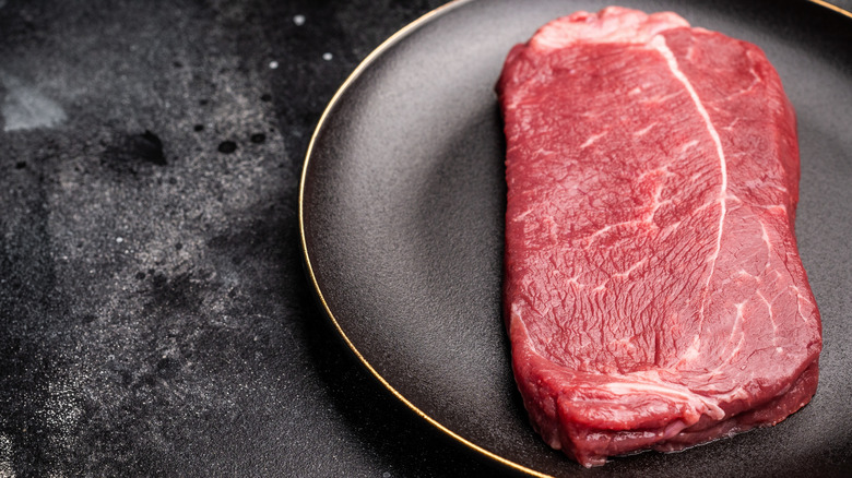 A piece of beef rump roast steak on a black plate