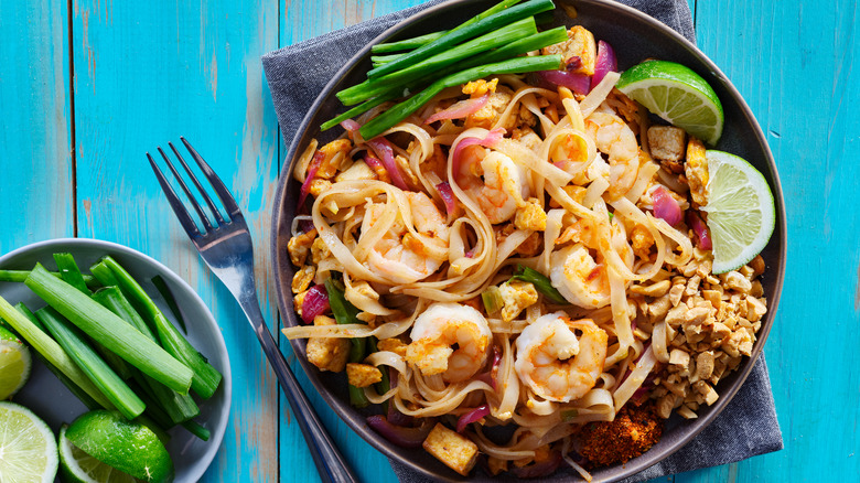 Thai noodle dish with shrimp, limes, and peanuts