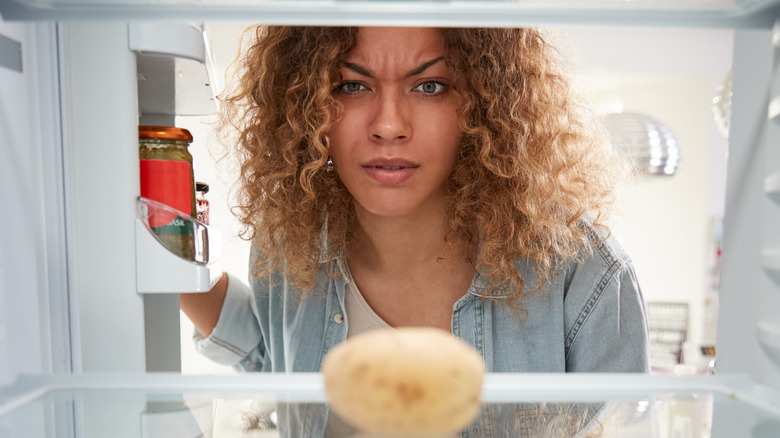 woman looking at potato in fridge