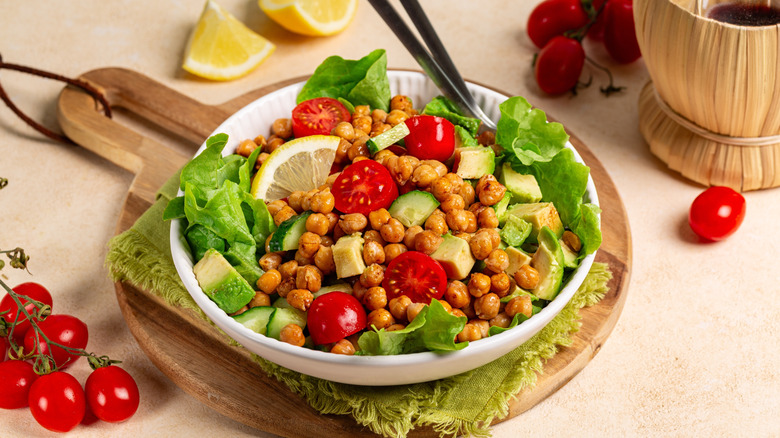 Bowl of chickpea salad with tomatoes, cucumber, lettuce, and avocado