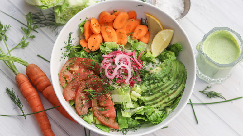 Bowl of salad next to green goddess dressing