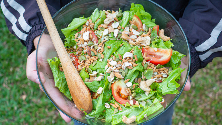 Hands holding bowl of salad with seeds