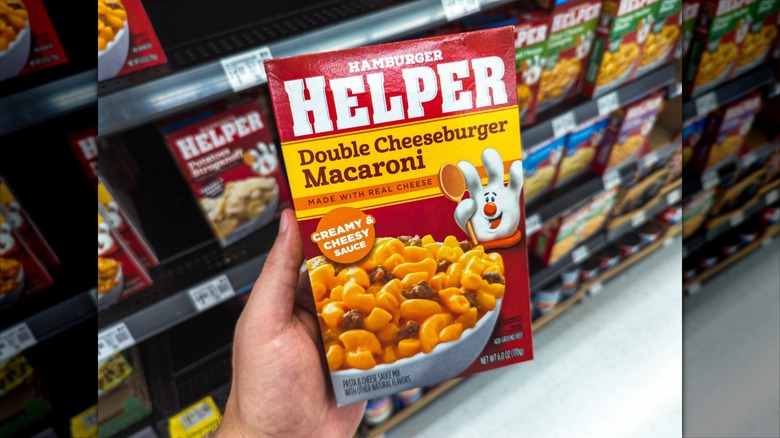 person holding box of hamburger helper in grocery store