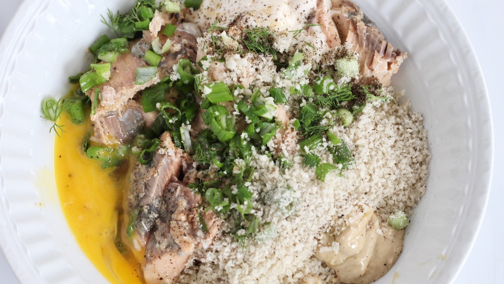 Ingredients for salmon patties added into large white bowl