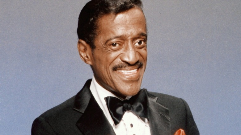 Sammy Davis Jr. smiling and pointing during photoshoot.