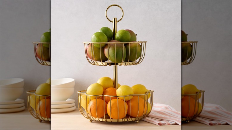 A two-tiered wire storage basket holding fruit.