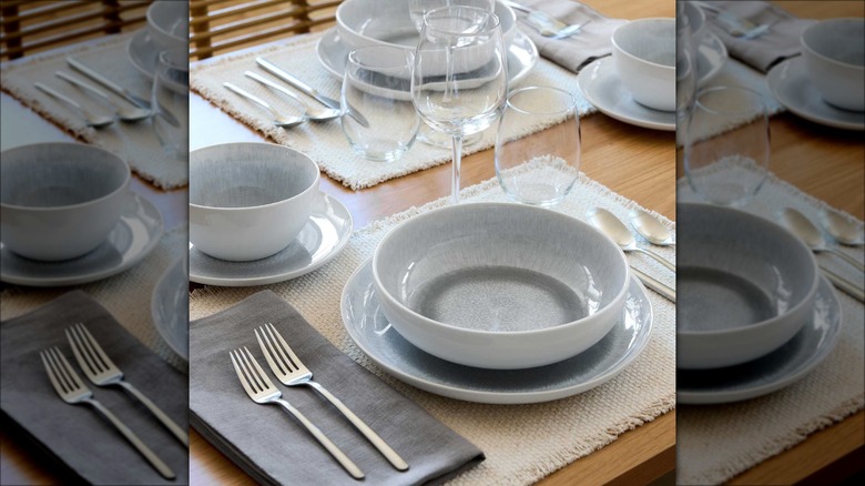 A stoneware pasta bowl set on table with place settings.