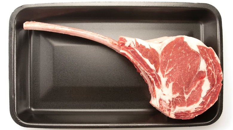 A raw Sam's Club cowboy ribeye steak in its container