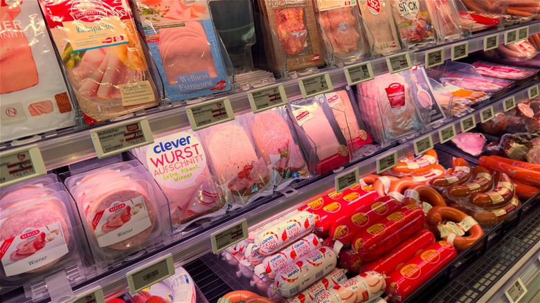 Assorted packaged deli meats on display in a supermarket chiller.