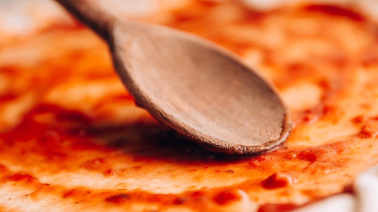 wooden spoon spreading red sauce