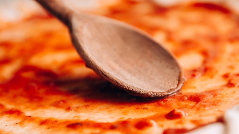 wooden spoon spreading red sauce