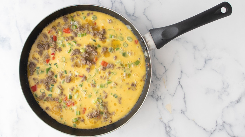 eggs, sausage, and vegetables in pan