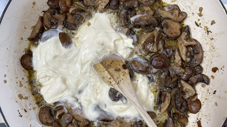 white creamy substance being stirred into mushrooms