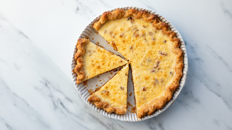 quiche di pancetta e cipolla in una tortiera con pezzi tagliati