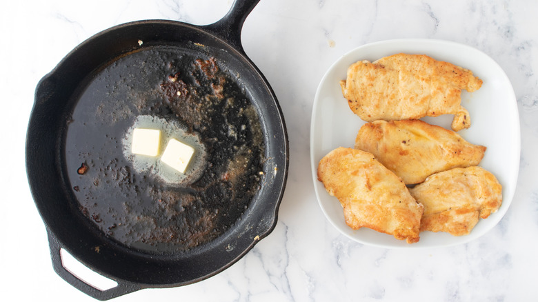 melting butter in skillet with seared chicken on plate