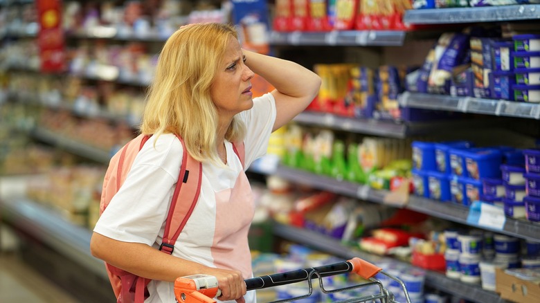 Distressed woman looks at grocery shelves