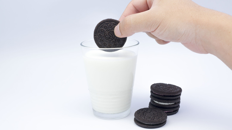 Hand dunking Oreo into glass of milk