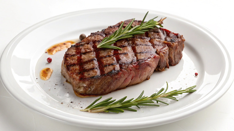 Garnished steak on white plate against white background