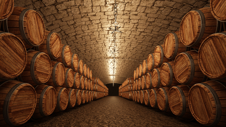 A cellar room lined with wooden barrels for aging spirits