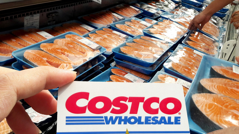 hand holding costco card in front of fish filets