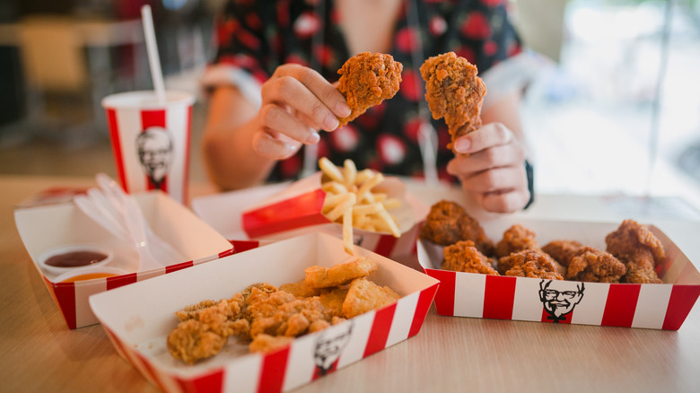 holding chicken drumsticks at KFC Thailand 