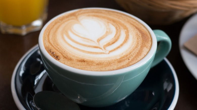 Cappuccino in foam green cup and black saucer