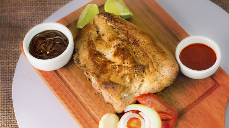 Grilled pork on a platter with sauces