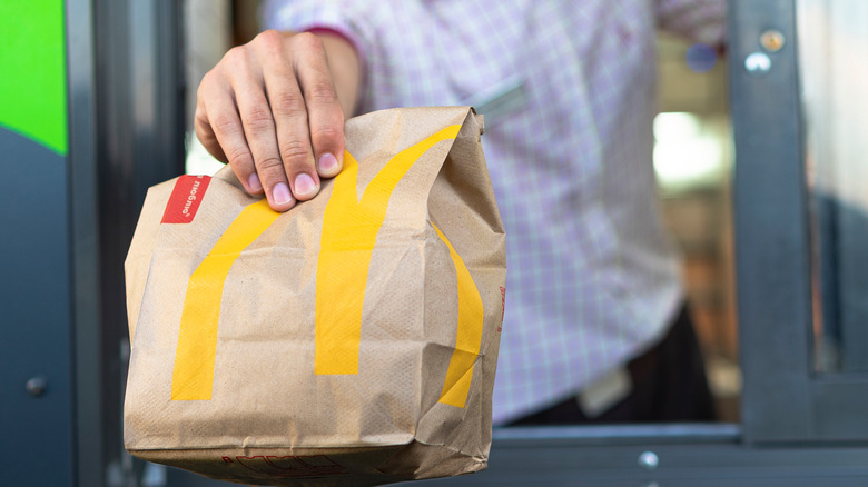 hand holding McDonalds bag out of a drive through window